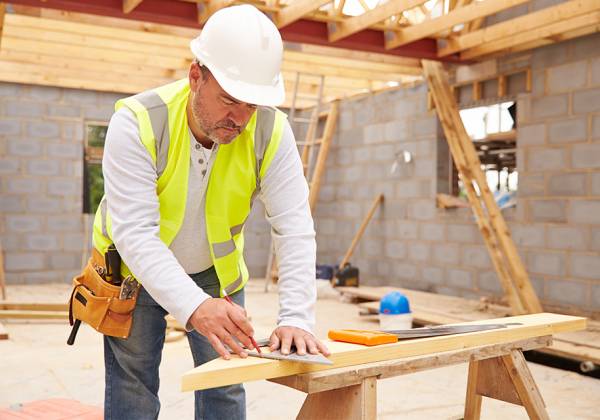 Man in hi-vis vest and hard hat working on a building site.